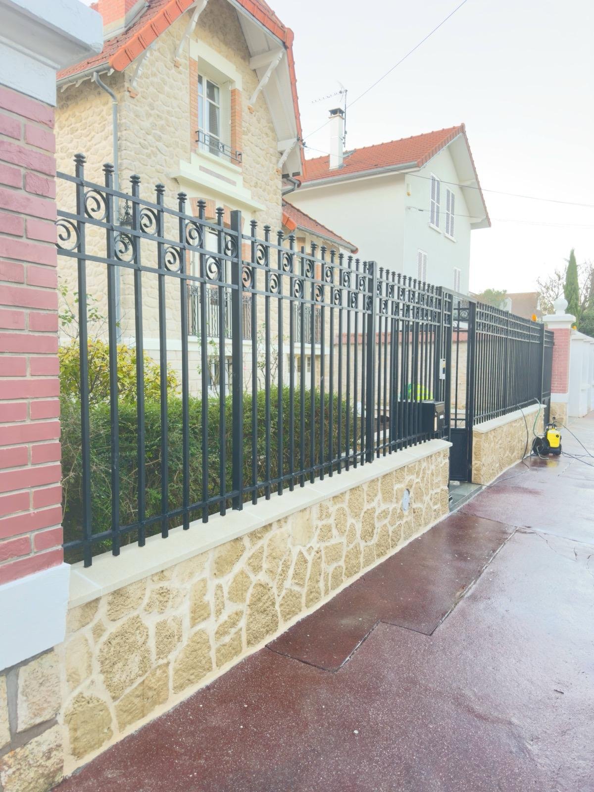 Clôture achevée avec parement pierre, couvertine et grille métallique noire